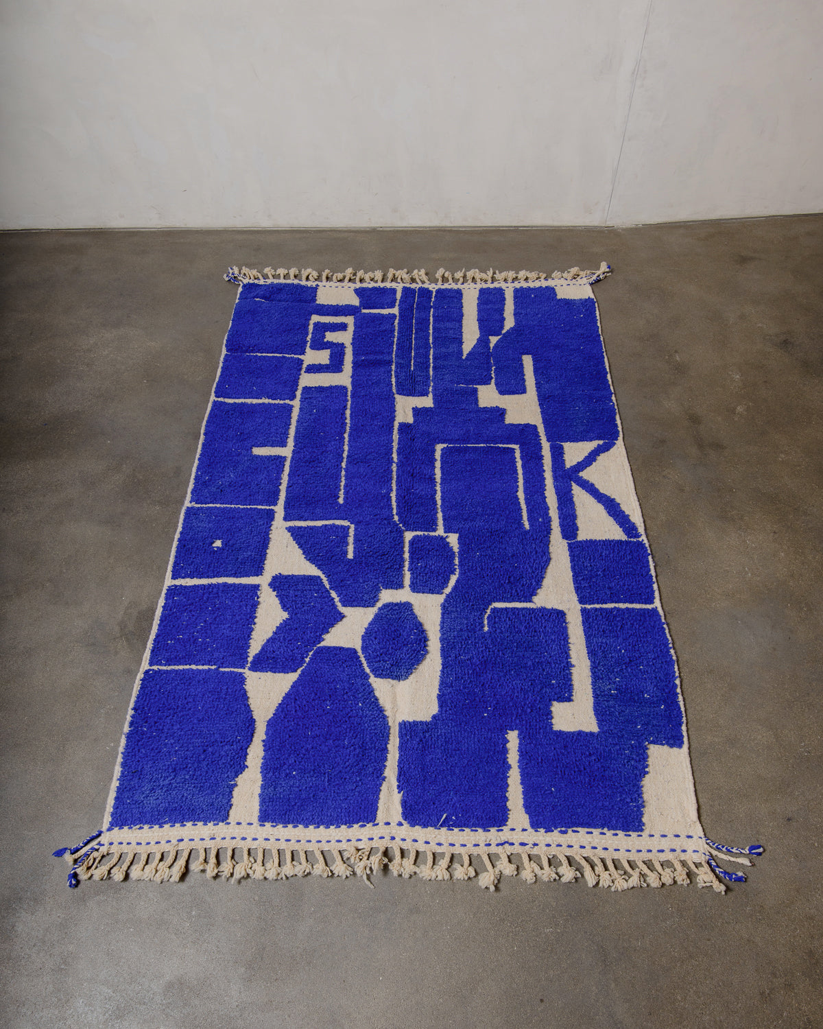 Berberlin Beniourain rug in cobalt blue and cream, laying flat on concrete floor.